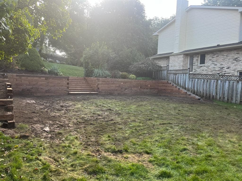Wood timber retaining wall with built-in steps creating a terraced backyard grade change