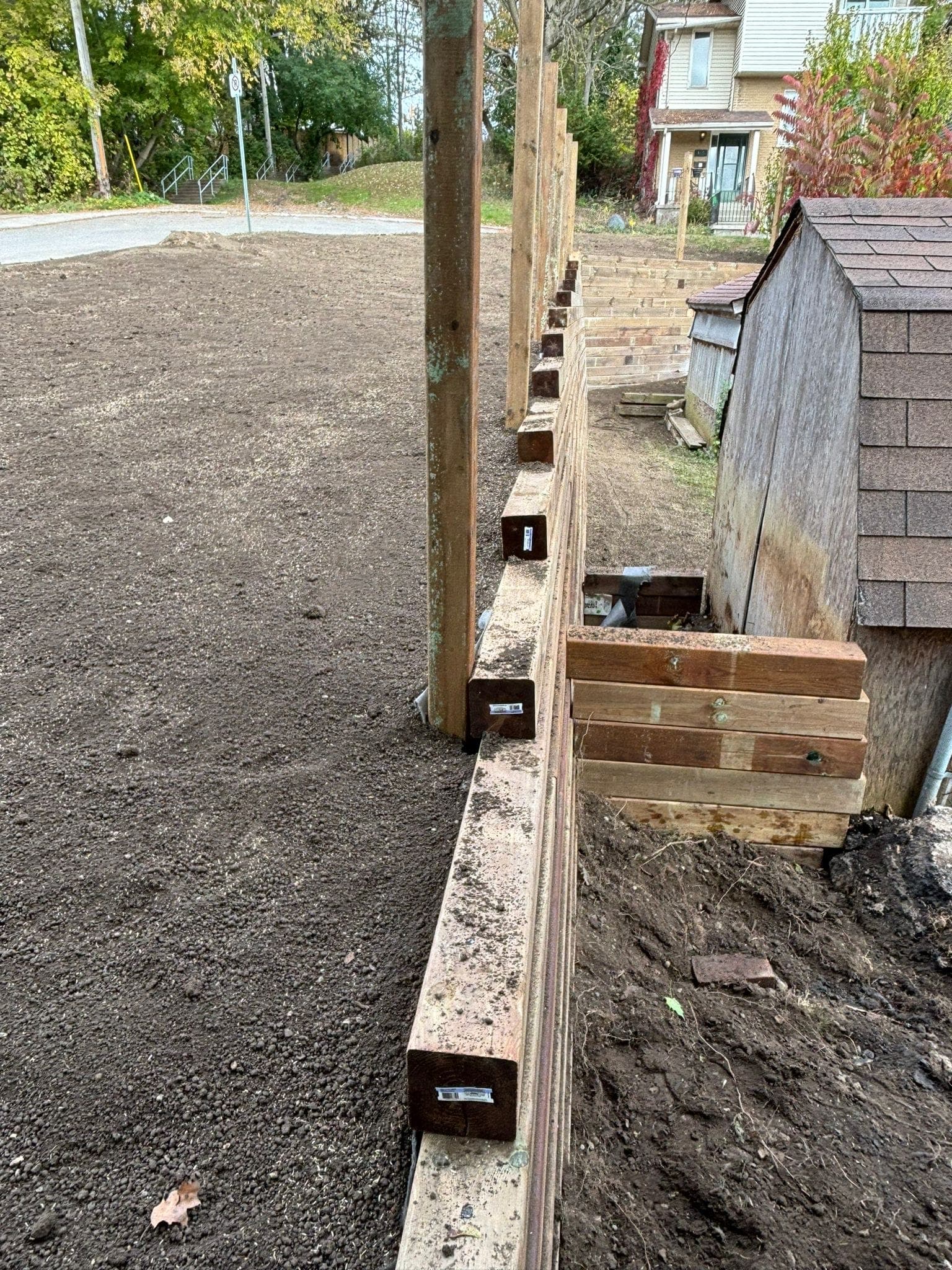 Pressure-treated timber retaining wall with vertical support posts holding back a graded yard