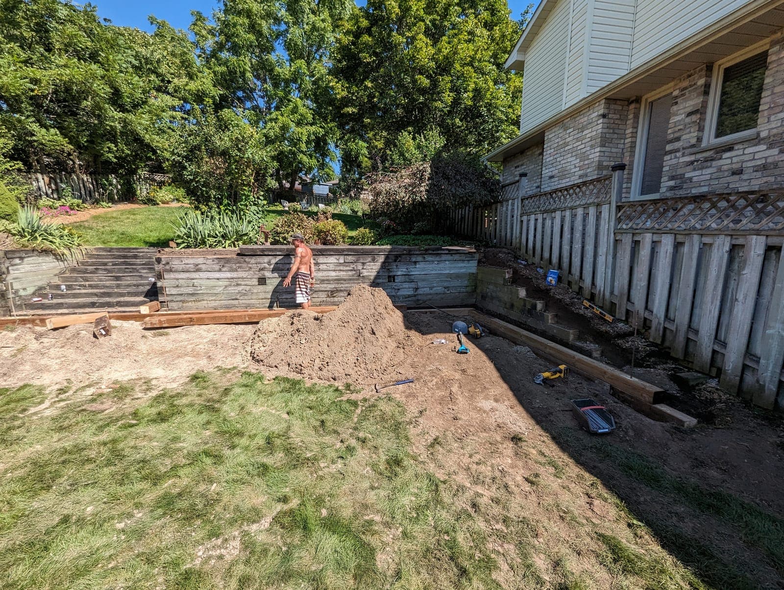 Weathered timber tie retaining wall holding back a raised backyard garden bed during a landscaping project
